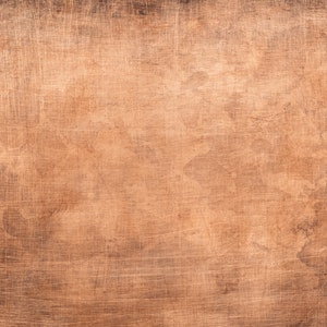 Op de afbeelding: Een close-up van een getextureerd koperen oppervlak met een warme, roodbruine kleur. Het oppervlak heeft een subtiele glans en een licht ruwe textuur.