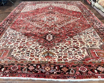 May include: Large, rectangular, antique rug with a central medallion design. The rug features a predominantly red and ivory color palette with intricate floral and geometric patterns. The border is a dark brown with repeating shapes.