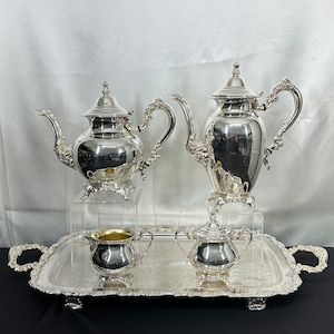May include: A silver tea set with a teapot, creamer, sugar bowl, and a serving tray. The set has a traditional design with ornate details.
