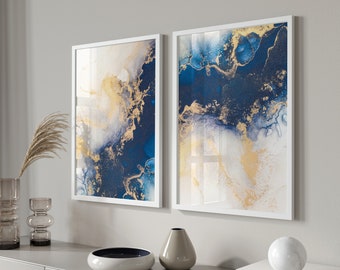May include: Two framed abstract art prints with white frames. The prints feature a blue and gold marbled design.