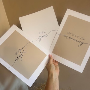 May include: Three rectangular wall art prints featuring a beige center panel with a white border. The prints display black text in a mix of serif and script fonts: "night night", "LOVE you", and "SEE YOU IN THE morning" written in a flowing style.