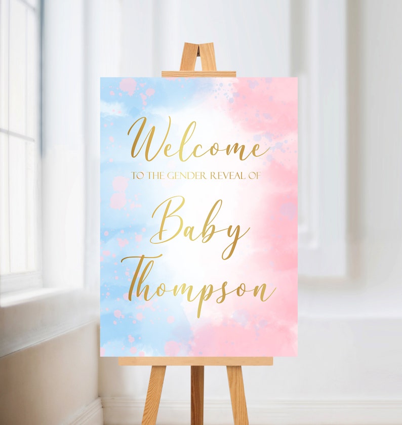 May include: Welcome to the gender reveal of Baby Thompson sign with a blue and pink watercolor background. The text is in gold.