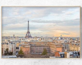 May include: A framed print of Paris featuring the Eiffel Tower. The image shows a cityscape with buildings and a cloudy sky. The Eiffel Tower is central, with a light brown frame.