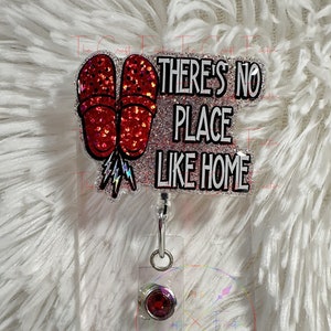 May include: Red glitter flip flop charm with a silver lightning bolt and the text "THERE'S NO PLACE LIKE HOME" on a white background. The charm is attached to a silver retractable badge holder with a red gem.