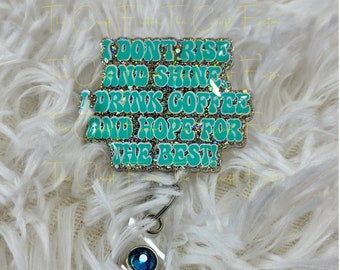May include: A teal blue glitter badge holder with the text "I don't rise and shine I drink coffee and hope for the best!"