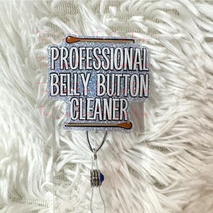 May include: A silver glitter badge holder with a silver and brown glitter stick figure holding a cotton swab. The badge holder has the text "Professional Belly Button Cleaner" printed on it.