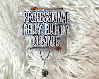 May include: A silver glitter badge holder with a silver and brown glitter stick figure holding a cotton swab. The badge holder has the text "Professional Belly Button Cleaner" printed on it.