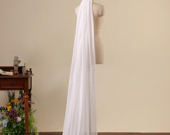 May include: A long, floor-length white wedding veil made of sheer, lightweight fabric. The veil is draped over a beige mannequin torso, extending from the top of the head down to the floor, creating a smooth, flowing silhouette with soft folds.