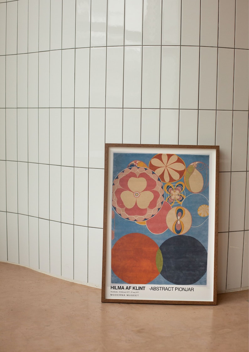 May include: A framed poster featuring a colourful abstract design with circles and flowers. The poster is titled "HILMA AF KLINT - ABSTRACT PIONJAR" and includes the text "Moderna Museet".