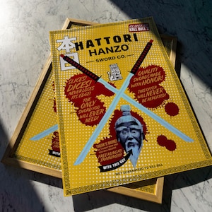 Könnte beinhalten: Ein gelber und roter Poster mit dem Text "HATTORI HANZO SWORD CO." und einer Grafik von zwei gekreuzten Schwertern. Der Poster zeigt auch ein Cartoon-Bild einer Katze und eines Mannes mit langem weißem Bart. Der Text "SLICES! DICES! NEVER LOSES ITS EDGE!" und "THE ONLY SWORD YOU WILL EVER NEED!" ist ebenfalls auf dem Poster.