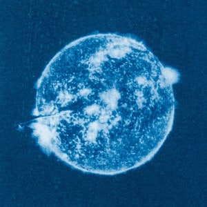 May include: A close-up of a blue and white image of the sun. The image is reminiscent of a vintage photograph.