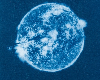 Puede incluir: Un primer plano de una impresión abstracta azul y blanca. La impresión presenta una forma circular con un centro blanco y un borde exterior azul. La impresión recuerda a un cuerpo celeste, como un planeta o una estrella.