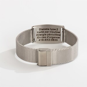 May include: Silver metal bracelet with a rectangular tag engraved with medical information in French. The tag reads "Diab&egrave;te type 2 trait&eacute; par insuline Allergie p&eacute;nicilline En cas d'urgence 418-8X3-0833".