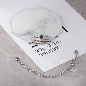 May include: A silver bracelet with a small silver tag engraved with the text "We engrave deeply to ensure the information would not fall off easily."