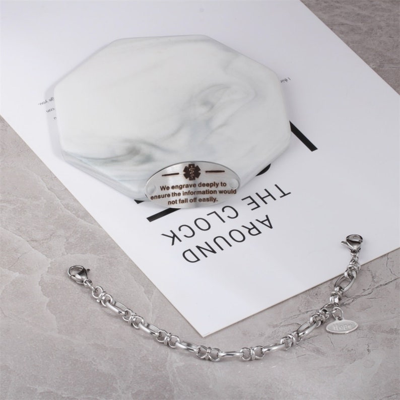 May include: A silver bracelet with a small silver tag engraved with the text "We engrave deeply to ensure the information would not fall off easily."