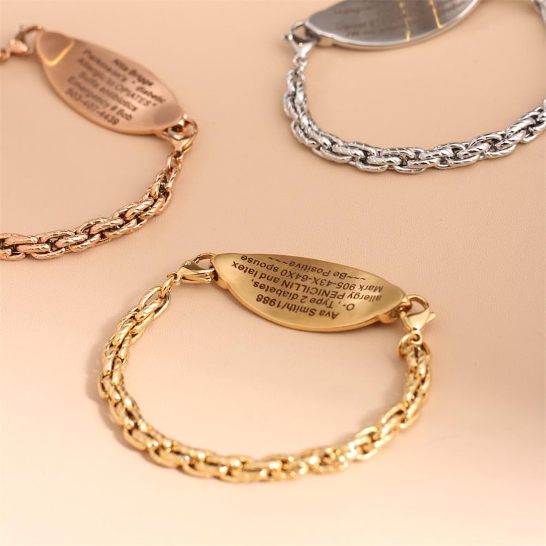 May include: Three medical alert bracelets featuring a textured chain link band and an oval-shaped metal identification plate. One bracelet is gold-toned, one is rose gold-toned, and one is silver-toned, each engraved with personal medical information.
