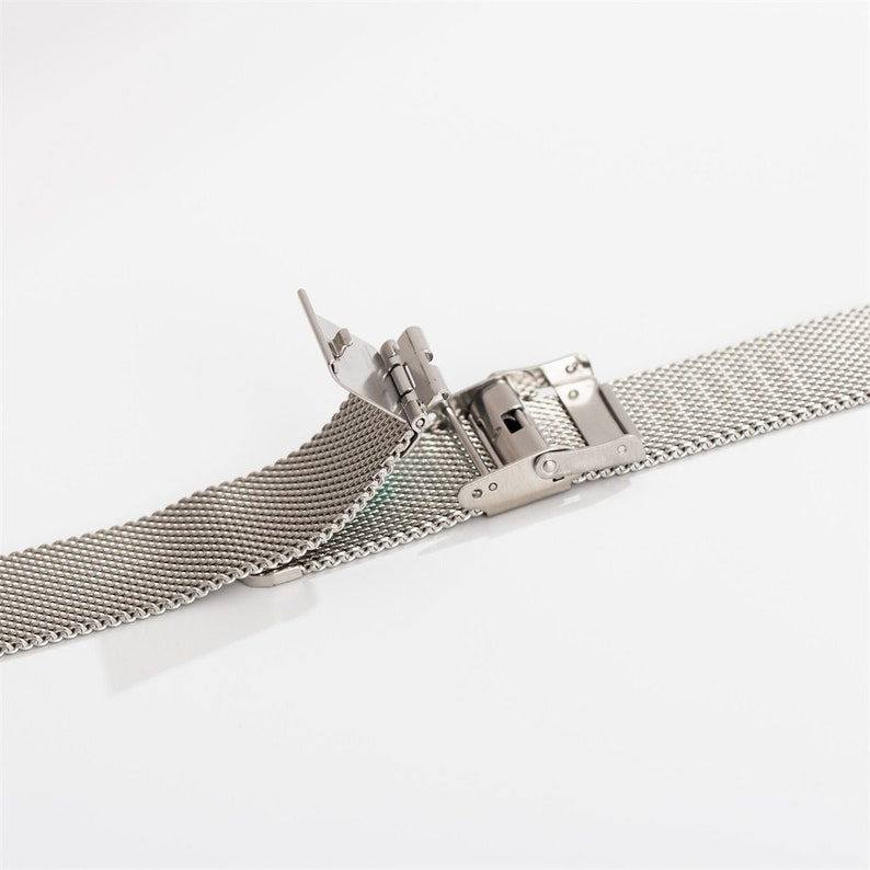 May include: A silver metal watch band with a clasp closure. The band is made of a fine mesh material.