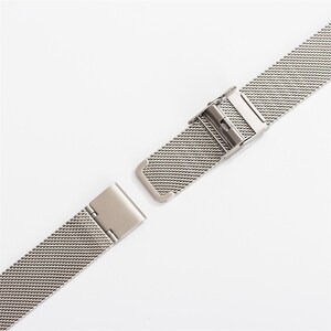 May include: A silver metal watch band with a clasp. The band is made of a fine mesh material.