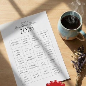 May include: A vision board bingo card for 2026 with various goals, a steaming mug of coffee, and a small bouquet of dried flowers. The card includes prompts like "Attend a concert" and "Make a new friend."