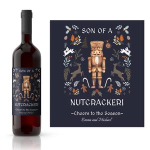 Könnte beinhalten: Ein Weinetikett mit einem festlichen Design, das einen Nussknacker, Schneeflocken und den Text "Son of a Nutcracker! -Cheers to the Season- Emma and Michael" zeigt.
