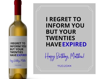 Könnte beinhalten: Eine Weinflasche mit rotem Verschluss und weißem Etikett. Das Etikett lautet "I REGRET TO INFORM YOU BUT YOUR TWENTIES HAVE EXPIRED" in schwarzer und blauer Schrift. Eine passende graue Karte mit dem gleichen Text befindet sich neben der Flasche.