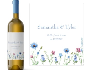Può includere: Una bottiglia di vino bianco con un'etichetta che dice "Samantha & Tyler" e "Bella Luna Farms" con una data. L'etichetta ha un bordo di fiori selvatici blu e rosa.