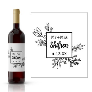 Puede incluir: Una etiqueta de botella de vino de boda en blanco y negro con diseños florales y el texto "Mr. + Mrs. Shifren 4.13.XX".