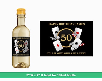 May include: A black and gold wine bottle label with a playing card design. The label says "Happy Birthday James" and "Still Playing With A Full Deck!" with the number 50 in a gold circle.