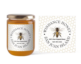 Può includere: Un barattolo di vetro di miele con un'etichetta bianca che dice "Windance Honey San Juan Island 100% Pure Organic Honey Net. Wt. 8 oz.". L'etichetta ha un motivo a nido d'ape e un disegno di un'ape.