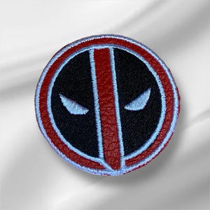 May include: Red and black embroidered patch with a white outline, featuring the iconic Deadpool mask.