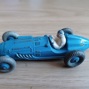 May include: A blue toy race car with a white driver figure. The car has a yellow 'A' on the side and the word 'LKY' printed on the side.