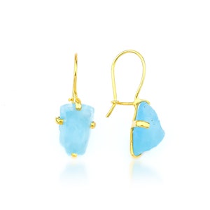 May include: Gold earrings with light blue aquamarine stones. The stones are irregular in shape and have a raw, natural look.