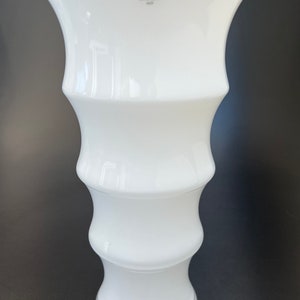 May include: White ceramic vase with a fluted design. The vase is marked with the logo "Holme Gaard 1825".