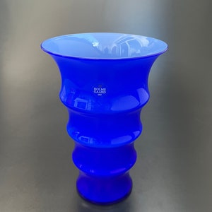 May include: A cobalt blue glass vase with a wavy design. The vase is made by Holme Gard, a Danish company founded in 1825.