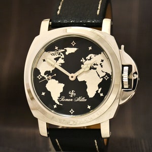 May include: A silver watch with a black face and a world map design. The watch has a black leather band and the words "Roman Miller" are printed on the face.