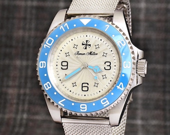 Può includere: Orologio da polso argentato con lunetta girevole azzurra e cinturino a maglia. Il quadrante è color crema chiaro con numeri neri e la scritta "Roman Miller". Le lancette e i dettagli della lunetta sono azzurri.