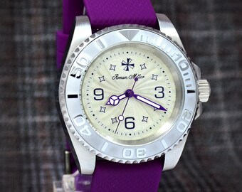 May include: Silver-toned wristwatch with a cream-colored face, featuring the brand name "Roman Miller". The watch has a purple band and hands, with star and cross-shaped hour markers. The bezel has numbers and markings.