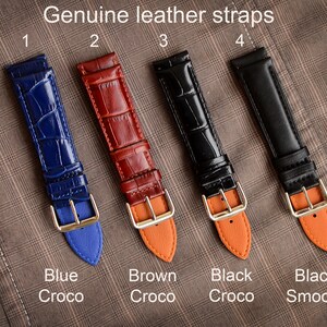 May include: Four genuine leather watch straps in blue, brown, black crocodile, and black smooth. Each strap has a gold-colored buckle and a contrasting color on the underside. The text "Genuine leather straps" is at the top, with color names below.