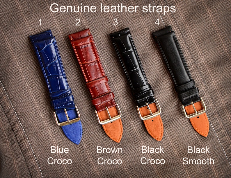 May include: Four genuine leather watch straps in blue, brown, black crocodile, and black smooth. Each strap has a gold-colored buckle and a contrasting color on the underside. The text "Genuine leather straps" is at the top, with color names below.