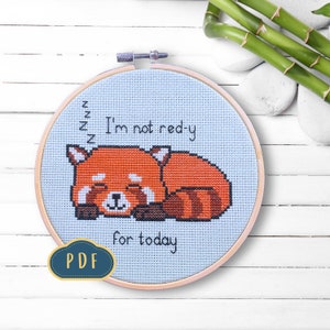 Könnte beinhalten: Ein Kreuzstichmuster mit einem schlafenden Roten Panda und dem Text "I'm not red-y for today" auf hellblauem Hintergrund.
