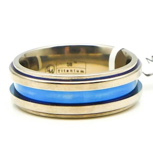 May include: A titanium ring with a blue inlay and a gold band. The ring is engraved with "58 Titanium".