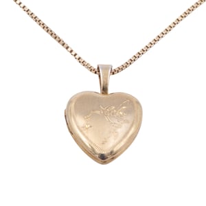May include: A gold-toned heart-shaped locket pendant suspended from a matching box chain. The front surface of the locket features an engraved illustration of a winged fairy figure holding a small star, framed by a delicate dotted border.