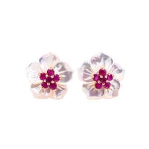 May include: A pair of stud earrings shaped like five-petaled flowers. Each earring features white iridescent mother-of-pearl petals surrounding a central cluster of five small, round, deep pink rubies set in a gold-toned metal base.