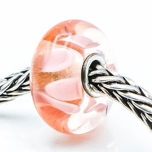 Peut inclure: Une perle en verre rose avec un motif en spirale. La perle est sur une chaîne en argent.