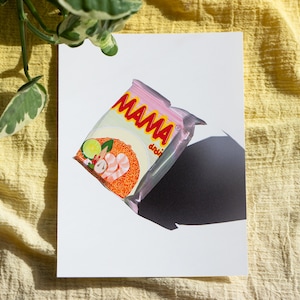 May include: A pink and red instant noodle packet with the word "MAMA" printed on it. The packet shows a bowl of noodles with prawns, lime, and other ingredients.