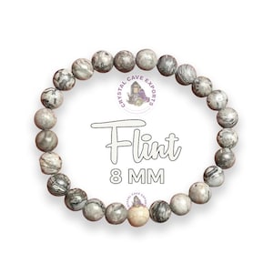 Puede incluir: Un brazalete de pedernal gris y blanco con cuentas de 8 mm. El brazalete está hecho de piedras naturales y tiene un diseño simple y elegante.