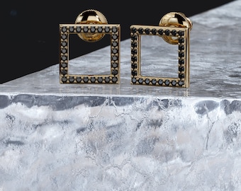 May include: A pair of gold square earrings with black diamond accents.