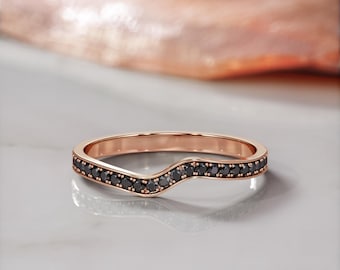 May include: A rose gold band ring with a curved design and a row of black diamonds.
