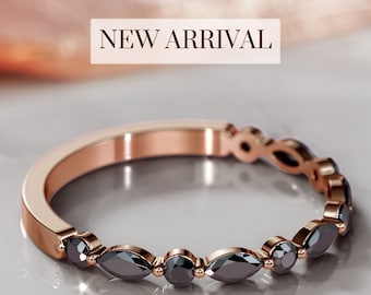 Op de afbeelding: Een roségouden bandring met een rij zwarte diamanten in marquise-vorm. De ring is nieuw en heeft een gepolijste afwerking.