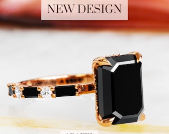 May include: Rose gold ring featuring a large, rectangular black gemstone. The band is adorned with smaller black and clear stones. The words "NEW DESIGN" and "ARAFEL" are displayed in the image.